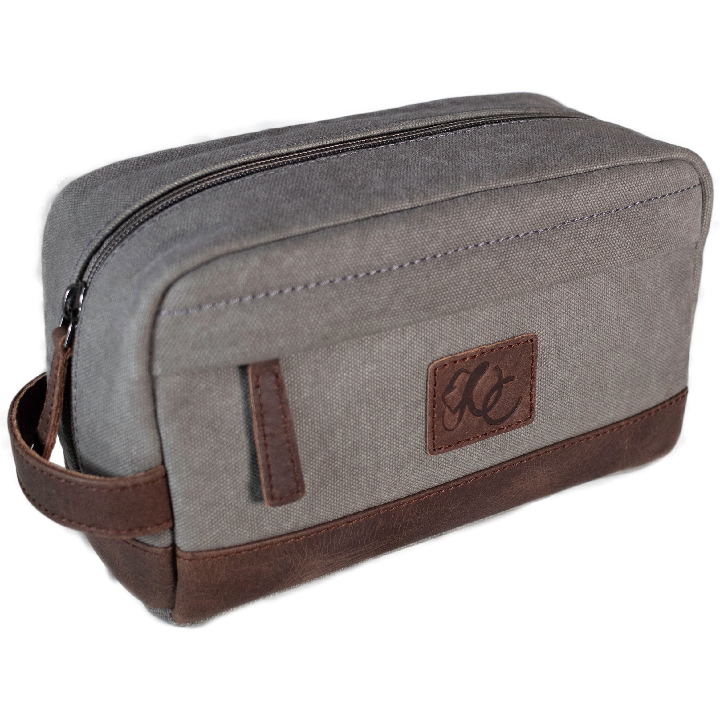 A grey canvas toiletry bag and brown leather details, featuring a zipper closure and a brand logo embossed on the front.