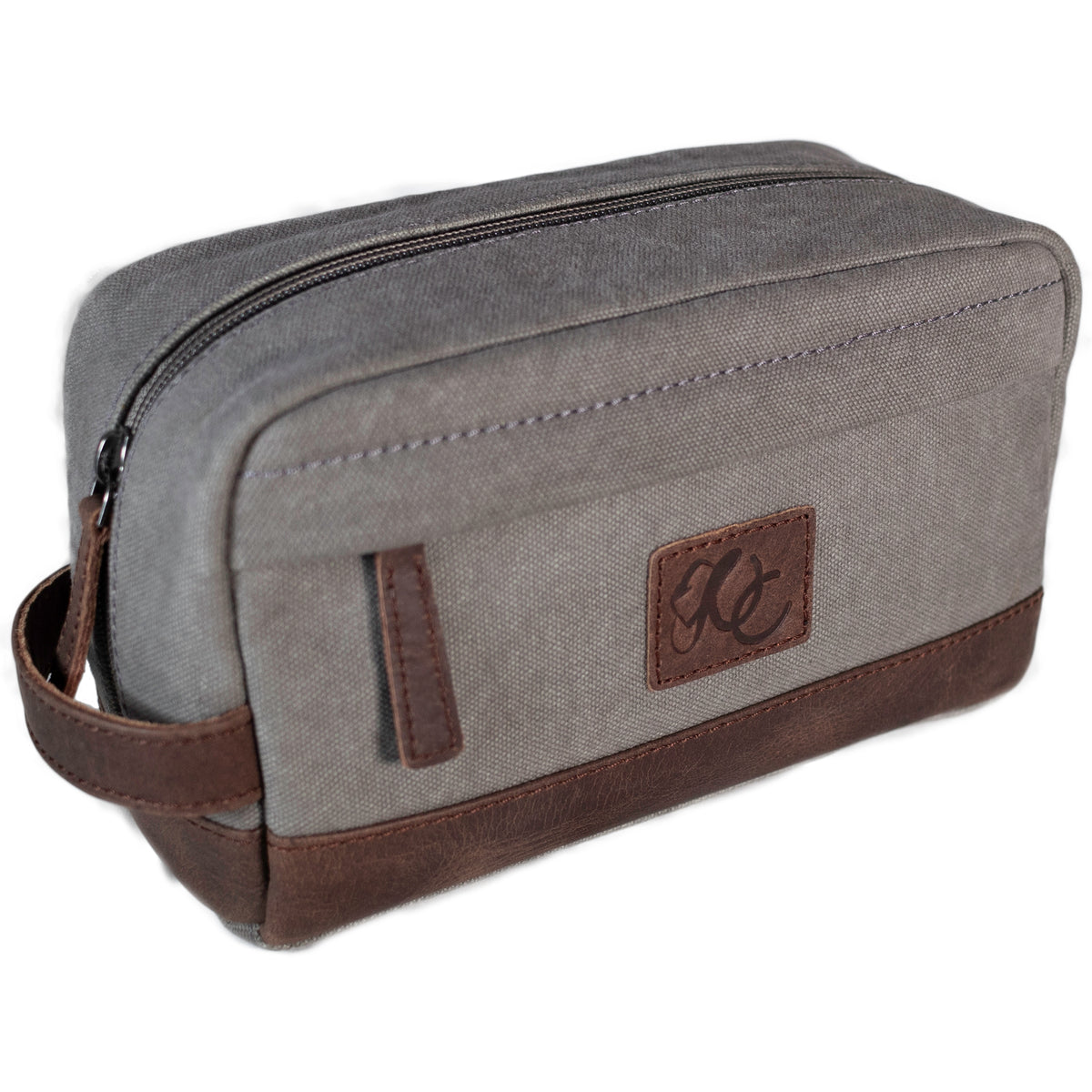 A grey canvas toiletry bag and brown leather details, featuring a zipper closure and a brand logo embossed on the front.