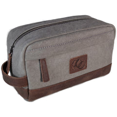 A grey canvas toiletry bag and brown leather details, featuring a zipper closure and a brand logo embossed on the front.