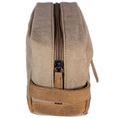 A brown canvas toiletry bag  and leather details, featuring a zipper closure and a brand logo embossed on the front.